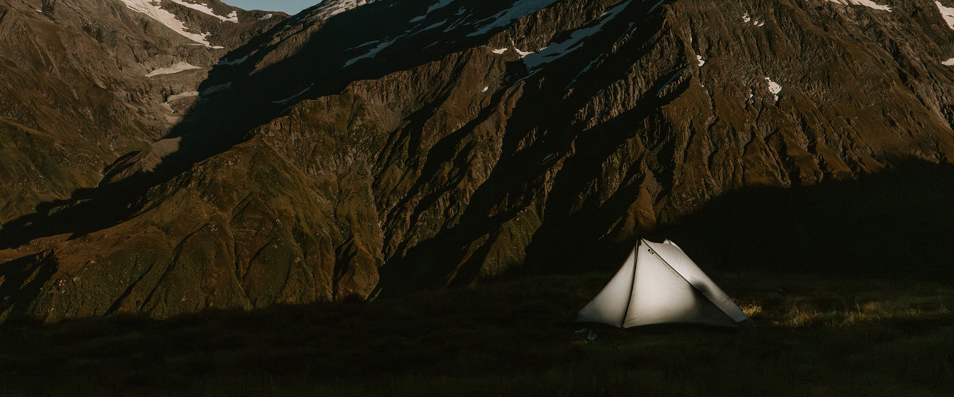 Camping tent in a mountainous area with snow-capped peaks